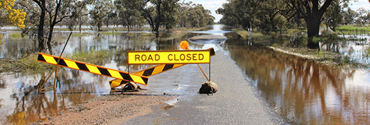 Road closed sign over a flooded road