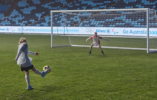 A child kicking a soccer ball into a goal