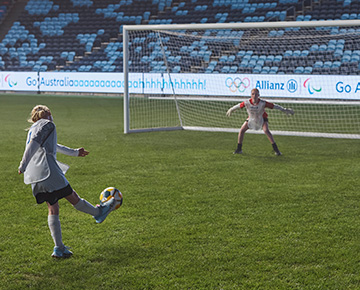 Young girl kicking a soccer ball into a gaol
