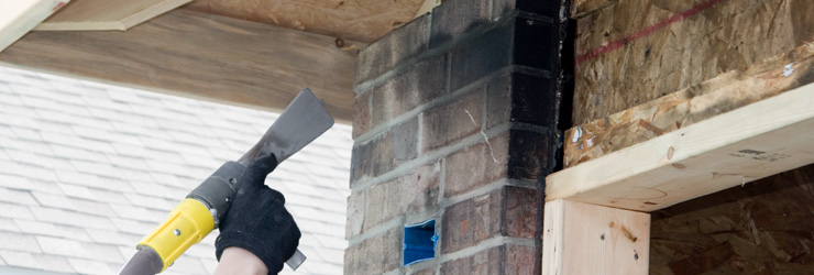 A hand with a tool to check if the exterior of a house is safe