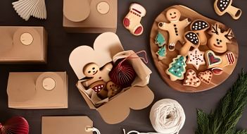 A selection of gingerbread biscuits in Christmas shapes with cardboard boxes.