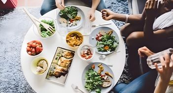 Three people sitting around a table to enjoy a vegetarian meal.