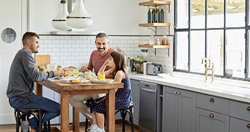 A smiling man carries his laughing daughter